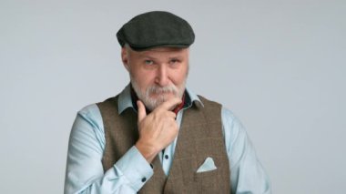 Zarif tüvit kumaşlı, orta yaşlı bir adam kameradan uzağa bakıyor, aşağıya bakıyor, rahatsızlık sinyali veriyor. Onun sofistike tarzı onun rahatsız edici davranışıyla çelişiyor. Kamera 8K HAM.