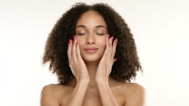 Afro bukleli çekici genç bayan, bronz tenli, bakımlı eli yumuşak cildinde kırmızı manikürlü, gözleri tutkuyla kapanıyor. Yüksek kalite 4k görüntü