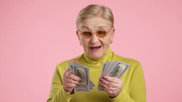 70年の高齢者によく育てられた見栄えの良い女性は 驚きの口を開き スタジオでピンクの背景の上に立っています 高品質の4K映像 — ストック動画