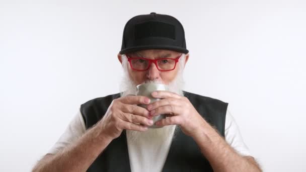 Пожилой Человек Белой Бородой Очках Шляпе Потягивающий Керамической Чашки Белом — стоковое видео
