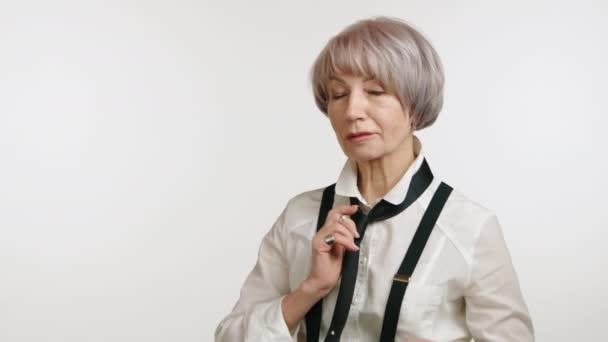 年富力强的老妇人摆出一副黑色领带和吊带的样子 穿着一件白色纽扣衬衫 流露出上流社会的气质和永恒的风格 高质量的4K镜头 — 图库视频影像