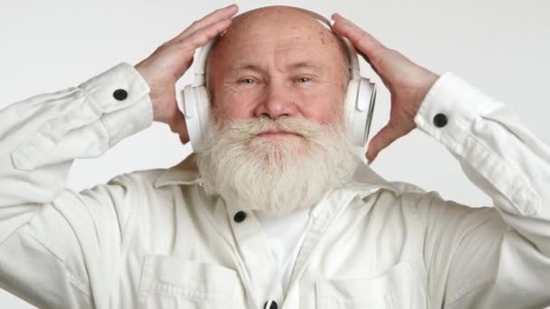 Idoso Sereno Usando Fones Ouvido Brancos Sorri Suavemente Seu Rosto — Vídeo de Stock