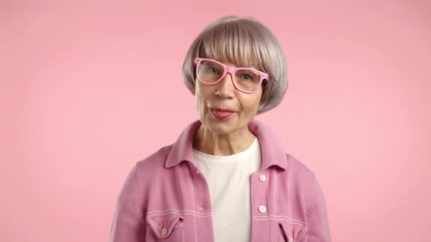 Starsza Kobieta Stylowych Okularach Wystaje Język Figlarnie Nosząc Żywy Różowy — Wideo stockowe