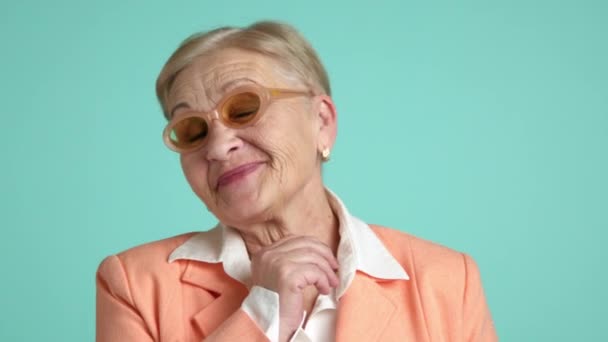 穿着时髦的桃色眼镜 身穿白衬衫 身穿桃色夹克 站在碧绿的背景下 卖弄风情的漂亮老太婆 高质量的4K镜头 — 图库视频影像