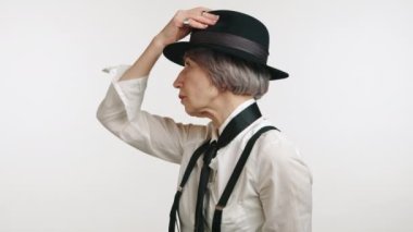 Çıtır beyaz gömlekli ve şapkalı olgun bir bayan. Şapkasının kenarı beyaz bir arka planda izole edilmiş. Yüksek kalite 4k görüntü