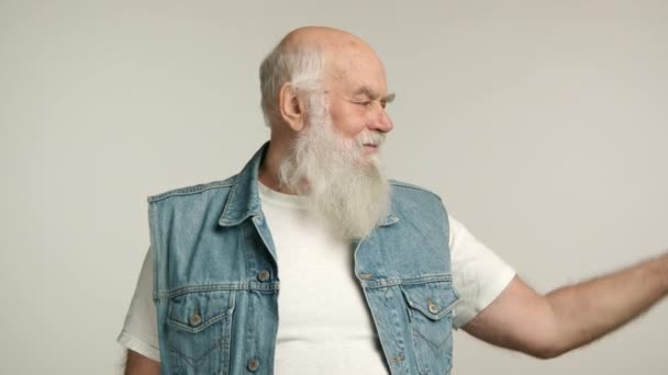 一个健壮的老年男子 留着浓密的白胡子 自信地穿着斜纹棉布背心弯曲着胳膊肌肉 象征着在白色背景下的力量和活力 8K照相机 — 图库视频影像