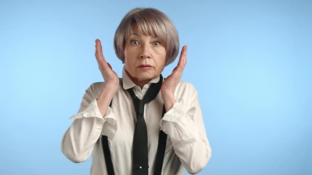 Μια Τρομαγμένη Ηλικιωμένη Γυναίκα Στέκεται Πάνω Ένα Μπλε Φόντο Χέρια — Αρχείο Βίντεο
