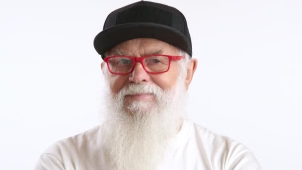 一位快乐的老人头戴黑色的帽子 戴着红色的眼镜 穿着宽松的白衬衫 面带微笑 散发出一种友善和平易近人的感觉 8K照相机 — 图库视频影像