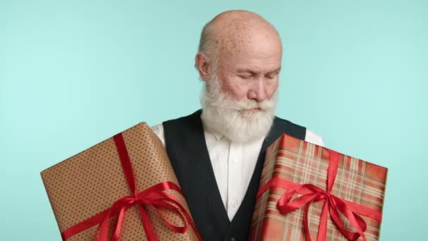 Сияющий Пожилой Человек Счастливо Преподносит Два Упакованных Подарка Лицо Выражает — стоковое видео