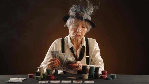 Äldre Kvinna Med Cigarett Mellan Tänderna Och Svart Hatt Räknar — Stockvideo