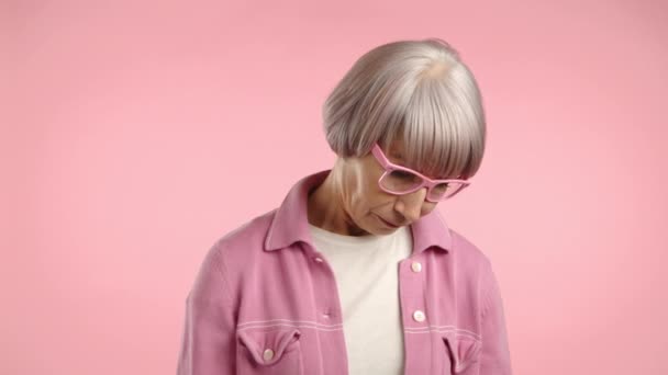 一个年事已高的女人显得很尴尬 她的面颊和她那件粉色衣服的腮红是相配的 那件衣服完美地混入了粉色的背景 8K照相机 — 图库视频影像