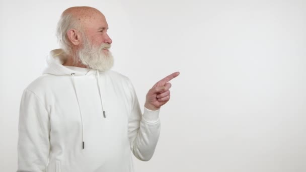 Okouzlující Starší Muž Lehkým Plnovousem Bílé Mikině Bílém Pozadí Ukazující — Stock video