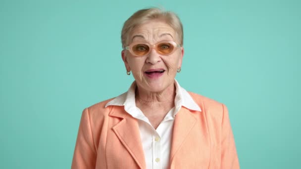 快乐的金发碧眼 满头皱纹 身穿白衬衫的60岁至70岁女性 橙色夹克转向相机 惊讶地张开嘴 凝视着相机 高质量的4K镜头 — 图库视频影像