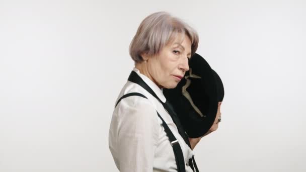 Elegante Seniorin Hosenträgern Selbstbewusst Mit Schwarzem Hut Vor Weißem Hintergrund — Stockvideo
