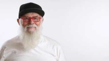 Şık şapkalı ve gözlüklü bir son sınıf öğrencisi temiz bir alana işaret ediyor. Yaratıcı reklamınızı el değmemiş beyaz bir tuvalde tanıtmak için ideal. Kamera 8K HAM. 