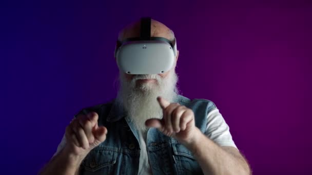 一名75岁的男子与虚拟物体互动 身穿斜纹棉布背心 衬托着充满活力的粉色和蓝色背景 展现了科技与老年生活方式的融合 8K照相机 — 图库视频影像