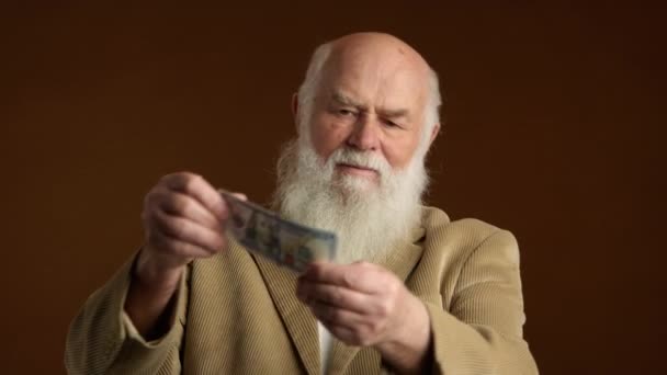 Bedachtzame Oudere Man Die Een Bankbiljet Onderzoekt Een Beige Trui — Stockvideo