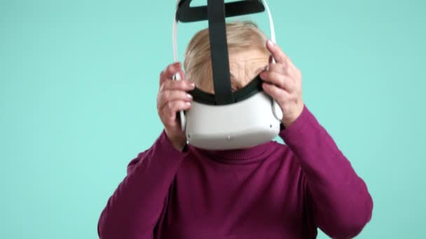 迷人美丽的老妇人被积极向上的情绪压垮了 在使用虚拟现实耳机后 站在蓝色的背景上 感到无比快乐 高质量的4K镜头 — 图库视频影像