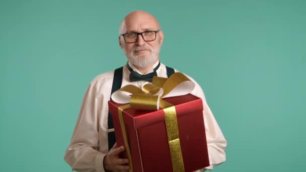 男人送上情人节礼物时 脸上洋溢着欢愉的表情 礼物包上金色的蝴蝶结 衬托在宁静而沉闷的背景下 8K照相机 — 图库视频影像
