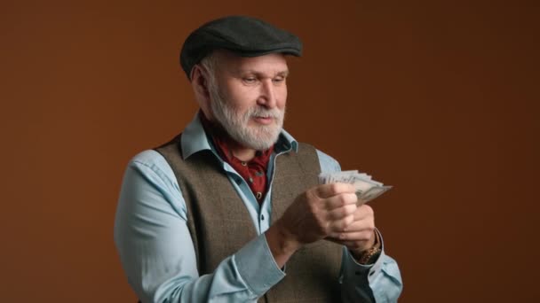 노련한 남자는 따뜻한 배경에 대하여 고전적인 조끼에 청구서의 소수를 계산으로 — 비디오
