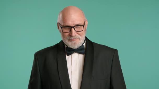一位优雅的 留着胡子的老人 戴着眼镜 身穿黑色燕尾服 在绿色的背景下点点头表示同意 高质量的4K镜头 — 图库视频影像