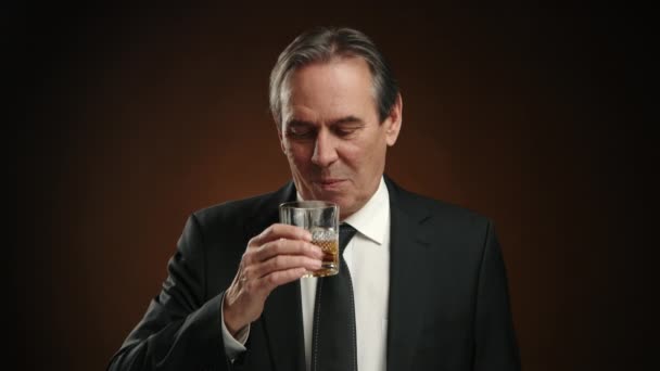 高価なウイスキーの味を味わう黒いスーツの成熟したビジネスマンは 贅沢さとリラクゼーションの感覚を反映しています カメラ Raw — ストック動画
