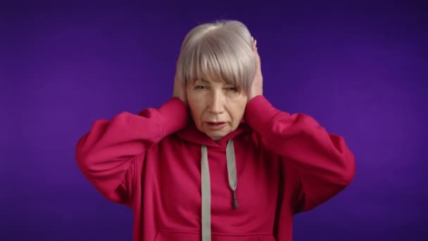 Senior Woman Vibrant Red Hoodie Hands Her Ears Wincing Grimacing — Stock Video
