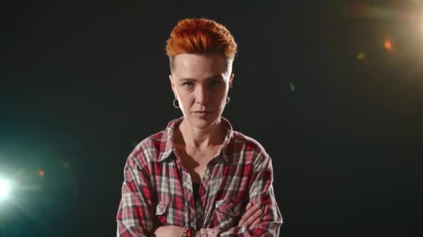一个快乐的女同性恋 红头发充满活力 被聚光灯照亮 在黑暗中闪烁着灿烂的微笑 穿着一件随意的格子衬衫 高质量的4K镜头 — 图库视频影像