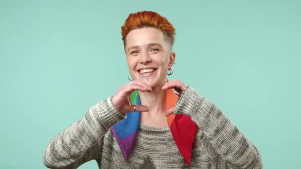 一个快乐的年轻女同性恋 有着醒目的红头发 她的双手形成了一个心形 在柔软的蓝色背景上散发着爱和积极向上的光芒 8K照相机 — 图库视频影像