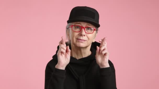 Μια Ελπιδοφόρα Ηλικιωμένη Κυρία Δάχτυλα Σταυρωμένα Μπροστά Ένα Παστέλ Ροζ — Αρχείο Βίντεο