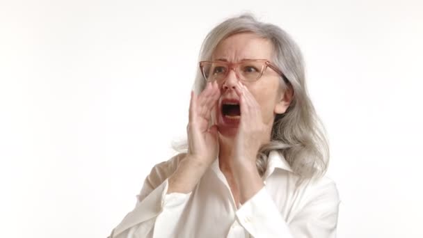 老年妇女大声喊着或双手捂着嘴喊着 试图把声音放大到很远的地方 被白色的背景隔开 8K照相机 — 图库视频影像