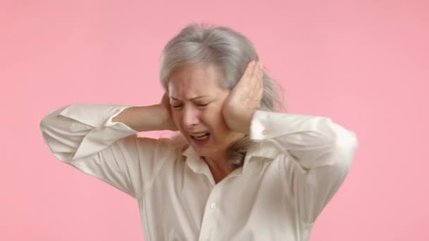 Äldre Kvinna Täcker Öronen Med Händerna Ett Smärtsamt Ansiktsuttryck När — Stockvideo