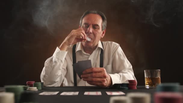 ポーカー テーブルの上のカードの組み合わせ タバコを持った男がカードを見て 試合に負けたことに気づく 彼は緊張し始め 相手に向かってカードを投げます カメラ Raw — ストック動画