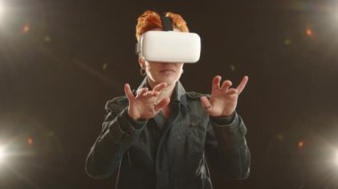 İfade eden bir jestle, VR kulaklık takan bir kadın sanal klavyede ustalıkla geziniyor, sanal ortama olan tutkusu ortada. Kamera 8K HAM. 