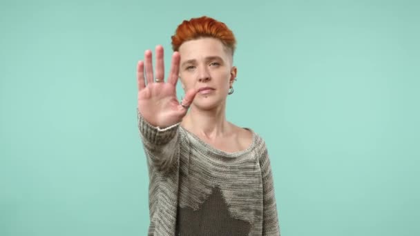 ユニークなヘアスタイルを持つ確固たるレズビアン女性は ミントグリーンの背景に彼女の拡張された手の信号境界に向かってしっかりと停止ジェスチャーを作ります カメラ Raw — ストック動画