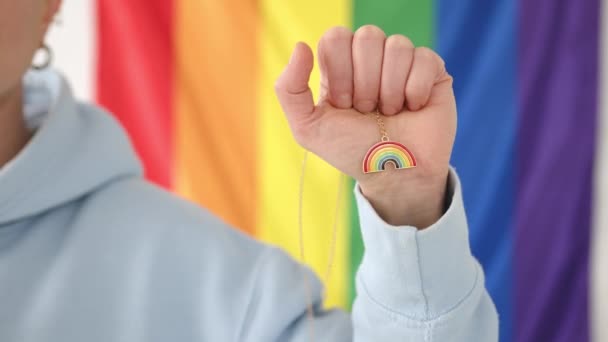 レズビアンの権利活動家としてのLgbtのプライドの本質は プライドフラッグの背景に設定された虹色のペンダントを慎重に保持しています 高品質の4K映像 — ストック動画