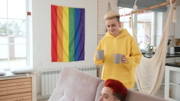两位处于同性恋关系中的女性在早晨的咖啡中分享着欢乐时光 在装饰着骄傲旗的客厅里 彼此微笑着 讲述各自的故事 高质量的4K镜头 — 图库视频影像