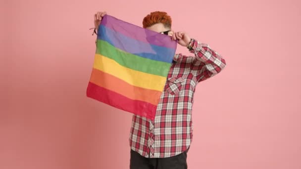 一位自信成熟的女同性恋 留着时髦的莫霍克发型 自豪地挥动着Lgbt骄傲的旗帜 在欢快的粉色背景下展示着她充满活力的精神 8K摄像头 高质量的4K镜头 — 图库视频影像