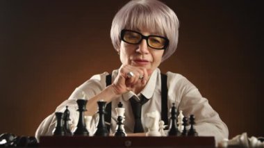 Olgun bir kadın satranç oyununa derinden odaklanır, sakin ve loş bir odada bir şövalyenin hareketini düşünür. Zarafet ve strateji onun oyununda birleşiyor. Kamera 8K HAM. 