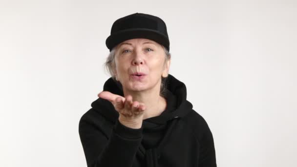 Eine Frau Mit Schwarzem Hut Und Kapuzenpulli Pustet Spielerisch Einen — Stockvideo