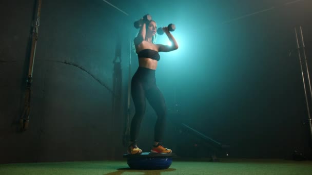 집중된 여성은 체육관에서 균형을 덤벨로 스쿼트를 운동으로 그녀의 안정성 근육을 — 비디오