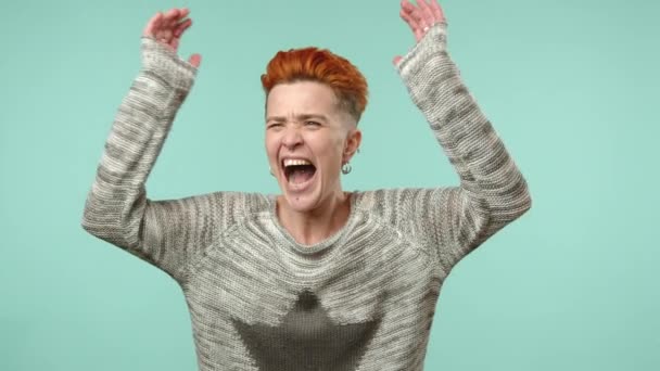 一个痛苦的女同性恋女人 有着独特的橙色的发型 她的耳朵和尖叫声 淹没在嘈杂的声音中 背景平静而沉闷 8K照相机 — 图库视频影像
