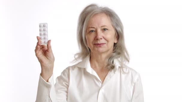 一位老年妇女仔细地检查了一包起泡的药丸 不以为然地摇了摇头 果断地放弃了药物 这表明了谨慎的健康管理的重要性 — 图库视频影像