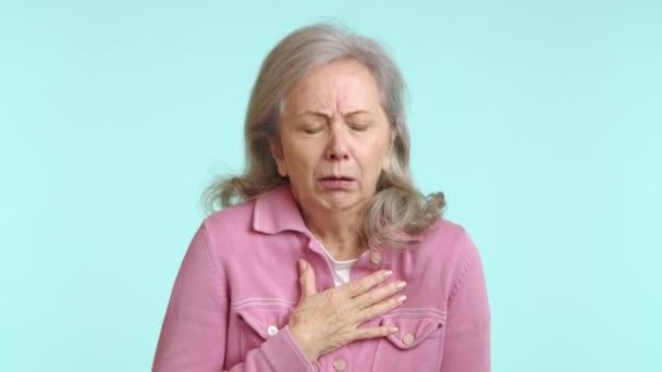 Starsza Kobieta Różowej Kurtce Wygląda Zmartwioną Gdy Kaszle Chwyta Się — Wideo stockowe
