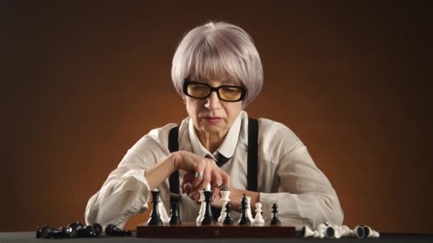 一位心事重重的老妇人犹豫着下棋的动作 脸上流露出很专注的表情 她的房间里有温暖而神秘的灯光 8K照相机 — 图库视频影像