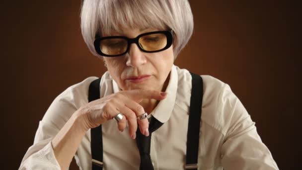 一位戴眼镜的老年妇女自信地在棋盘上捕获了对手的棋子 展示了她的战略思维和注意力 从正面到黑板的全景 — 图库视频影像