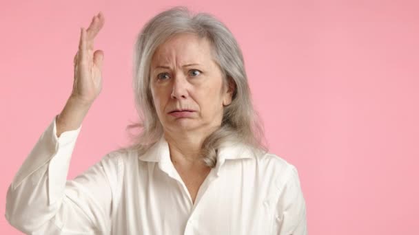 Eine Ältere Frau Weißer Bluse Steht Vor Einem Zartrosa Hintergrund — Stockvideo