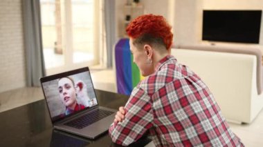 İç açıcı bir online etkileşim gösteriyor ki lezbiyen bir kadın video görüşmesi sırasında partnerine sanal öpücükler yolluyor, arka planda LGBT gurur bayrağı var, sevgi dolu atmosferi geliştiriyor.. 