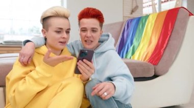 Romantik bir ilişkisi olan iki kadın yerde rahat bir şekilde otururlar ve akıllı telefondaki fotoğraflarla güzel anılarını izleyip paylaşırlar. Kamera 8K HAM. 