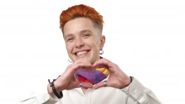 Parlak kızıl saçlı ve beyaz gömlekli bir lezbiyen, LGBTQ toplumundaki sevgi ve kabulü simgeleyen elleriyle bir kalp oluşturuyor. Kamera 8K HAM. 